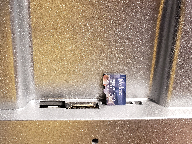 The back of a Meural canvas with a Micro SD card positioned above the Micro SD slot.